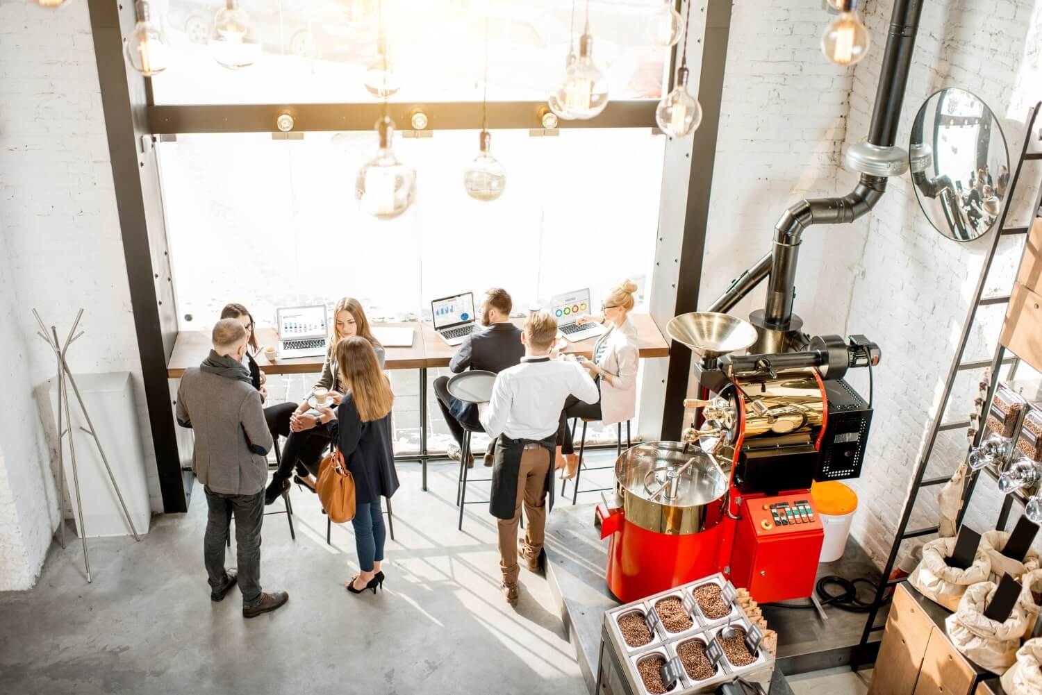 Interior de cafetería con clientes y tostadora de café